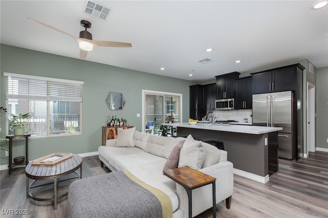 living area featuring recessed lighting, wood finished floors, visible vents, and baseboards