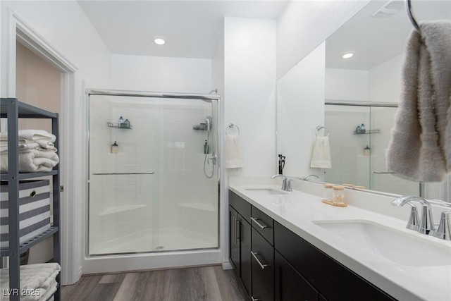 full bathroom with a sink, wood finished floors, a stall shower, and double vanity