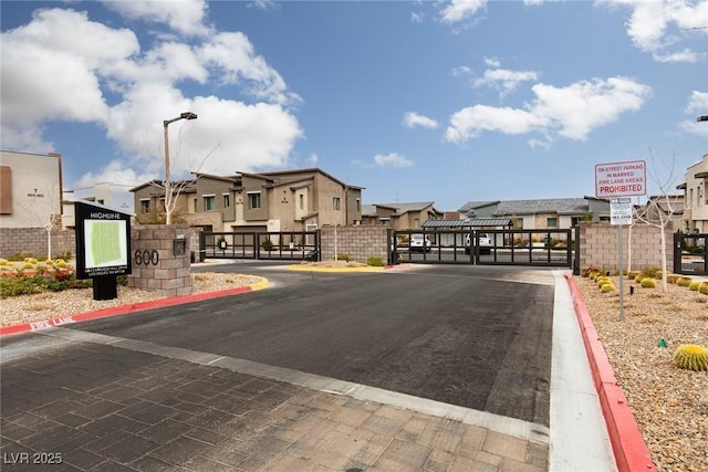 view of street with a gate, a residential view, street lighting, and a gated entry