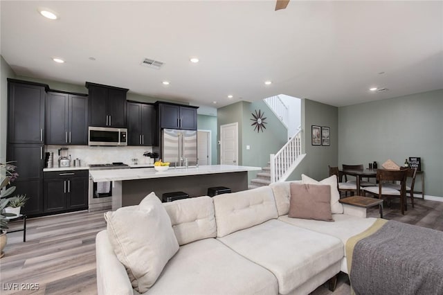 living area with recessed lighting, stairway, visible vents, and light wood finished floors