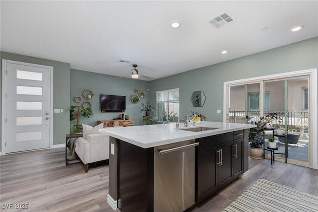 kitchen with a center island with sink, visible vents, a sink, stainless steel dishwasher, and open floor plan