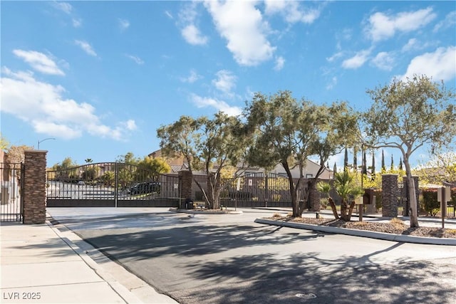 view of road with a gated entry, curbs, street lights, and a gate