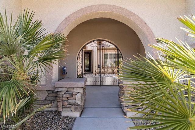 property entrance with stucco siding and a gate