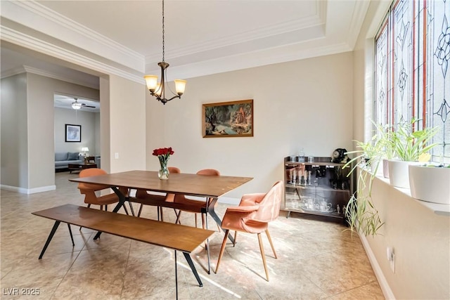 dining area with ceiling fan with notable chandelier, a raised ceiling, baseboards, and ornamental molding