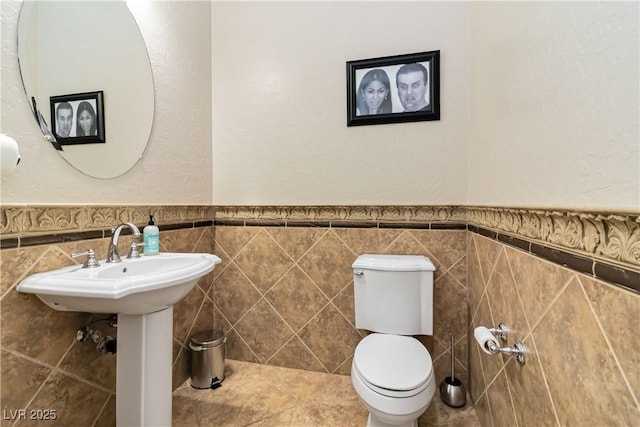 bathroom with tile walls, toilet, and wainscoting