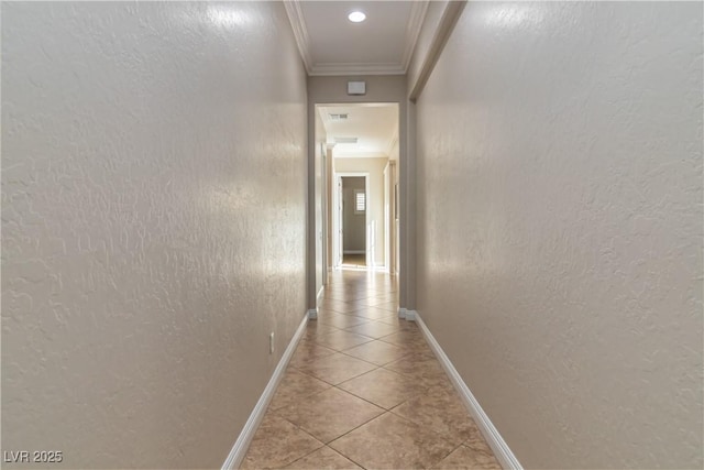 hallway with light tile patterned floors, crown molding, baseboards, and a textured wall