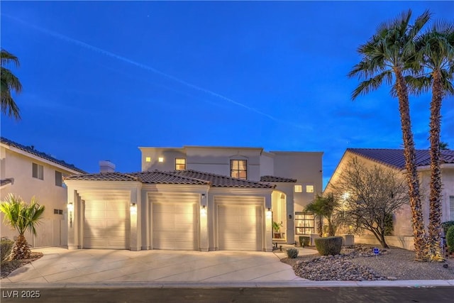 mediterranean / spanish-style house featuring a tile roof, a garage, driveway, and stucco siding