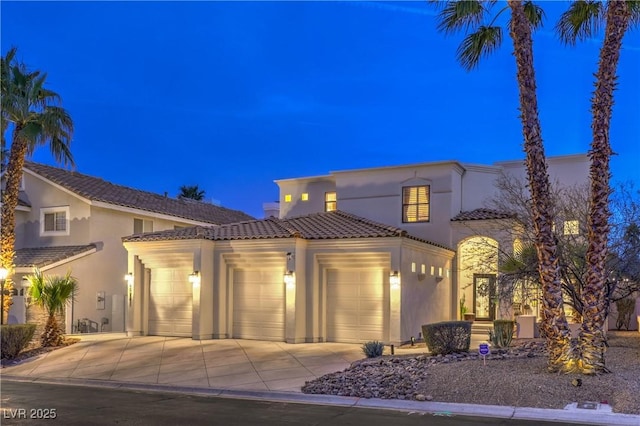 mediterranean / spanish-style home with a tiled roof, stucco siding, driveway, and a garage