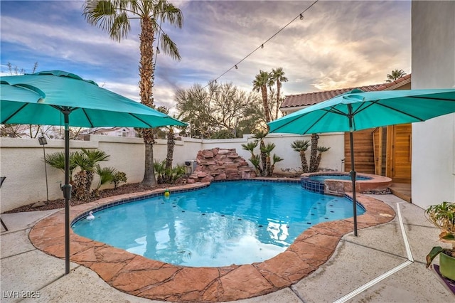 view of pool featuring a fenced backyard and a pool with connected hot tub