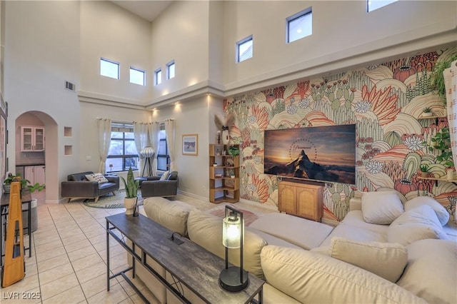 living room featuring arched walkways, light tile patterned floors, baseboards, and visible vents