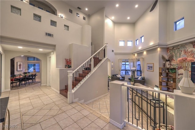 stairs featuring arched walkways, visible vents, tile patterned flooring, and recessed lighting