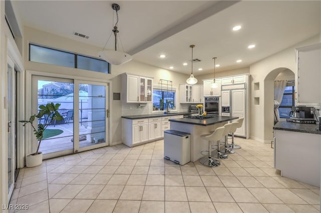 kitchen featuring visible vents, paneled refrigerator, dark countertops, black oven, and backsplash