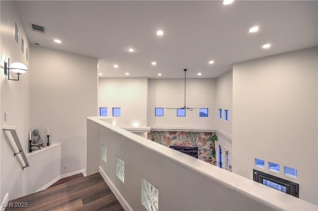 hall featuring visible vents, an upstairs landing, wood finished floors, recessed lighting, and baseboards