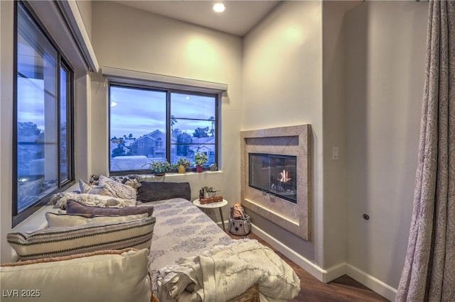 bedroom with a glass covered fireplace, baseboards, and wood finished floors