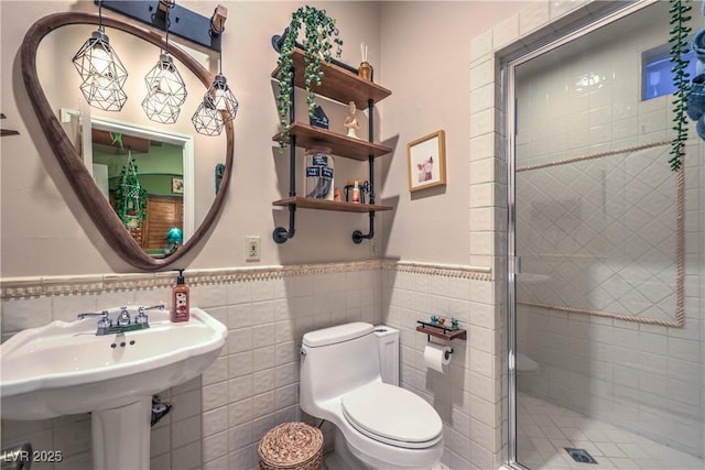 full bath with toilet, tile walls, a stall shower, and wainscoting