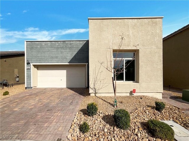 view of front facade with decorative driveway, a garage, and stucco siding