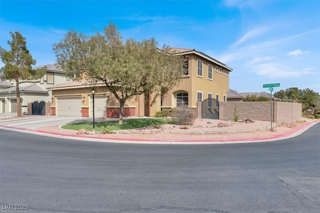 view of front facade with stucco siding, fence, concrete driveway, and a gate