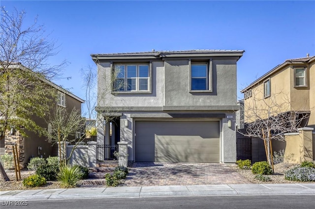 traditional home featuring stucco siding, decorative driveway, a garage, and fence