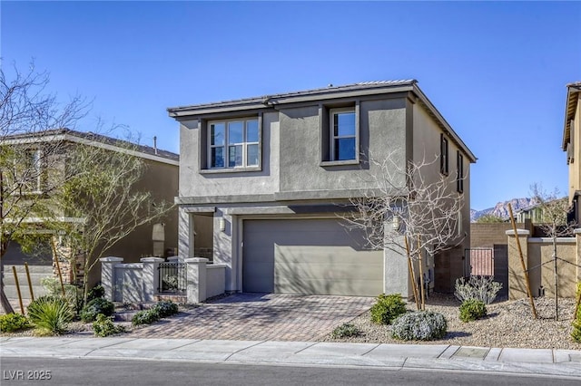 traditional-style home with stucco siding, decorative driveway, an attached garage, and fence