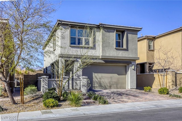 traditional-style house featuring decorative driveway, fence, a garage, and stucco siding