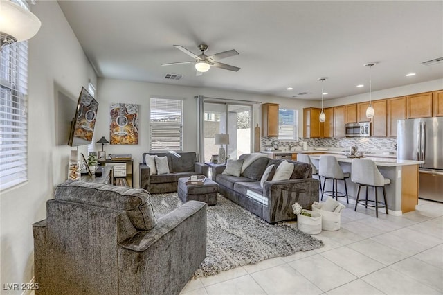 living area with light tile patterned floors, visible vents, and a ceiling fan