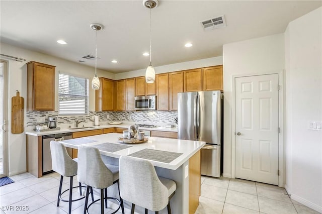 kitchen featuring visible vents, a breakfast bar, light countertops, decorative backsplash, and stainless steel appliances