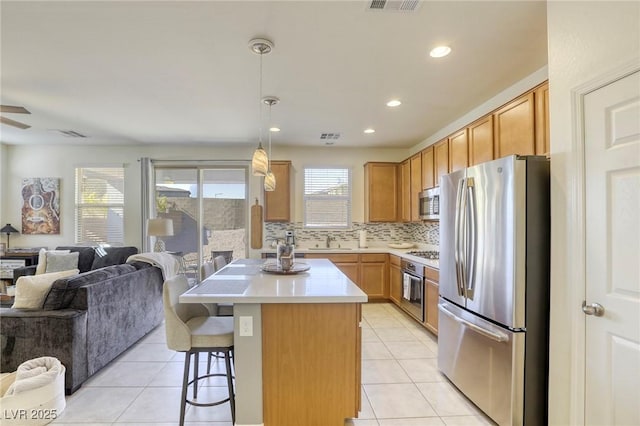 kitchen with light tile patterned floors, open floor plan, appliances with stainless steel finishes, and a sink