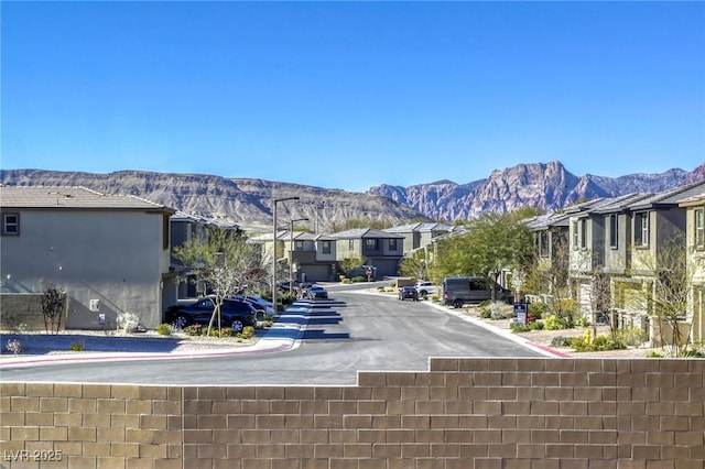 view of road with a residential view, curbs, and a mountain view