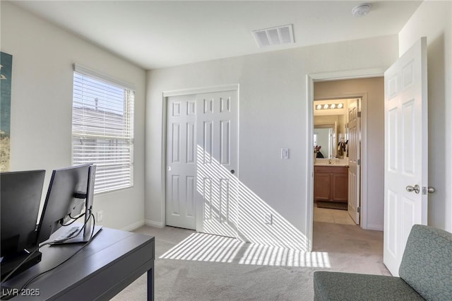 office featuring visible vents, light carpet, and baseboards