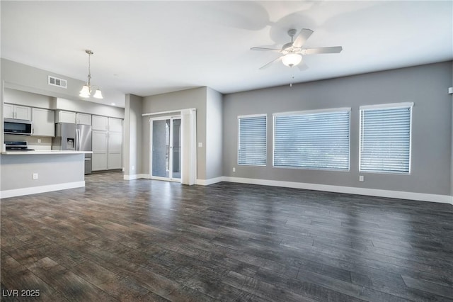 unfurnished living room featuring visible vents, baseboards, dark wood-style floors, and ceiling fan with notable chandelier