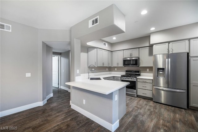 kitchen featuring visible vents, a peninsula, a sink, stainless steel appliances, and light countertops