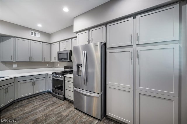 kitchen featuring visible vents, gray cabinets, dark wood finished floors, appliances with stainless steel finishes, and light countertops