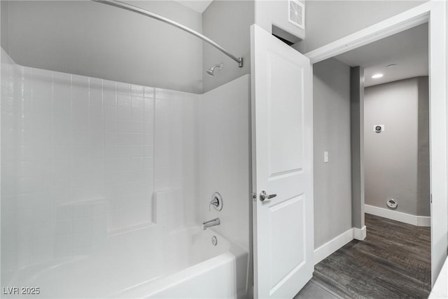 full bathroom with visible vents, washtub / shower combination, wood finished floors, and baseboards