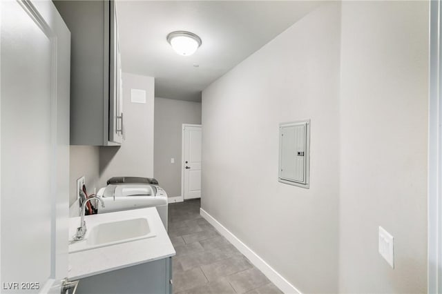 laundry room featuring electric panel, a sink, cabinet space, baseboards, and washer / dryer