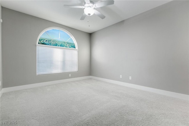 carpeted spare room with baseboards and a ceiling fan