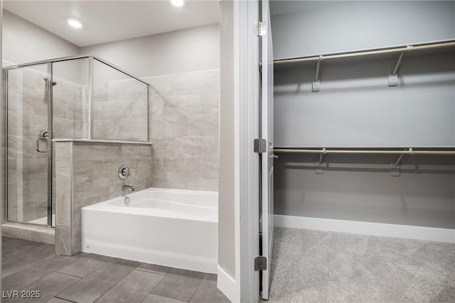 full bath with a spacious closet, a bath, and a shower stall