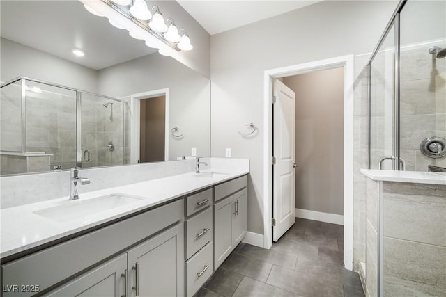 full bathroom with double vanity, baseboards, a stall shower, and a sink