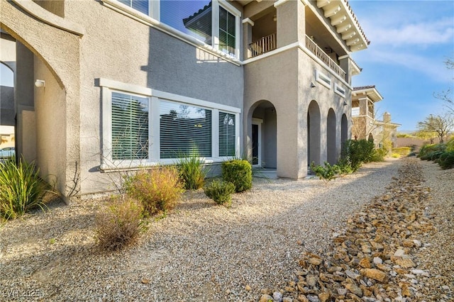 view of home's exterior with stucco siding and a balcony