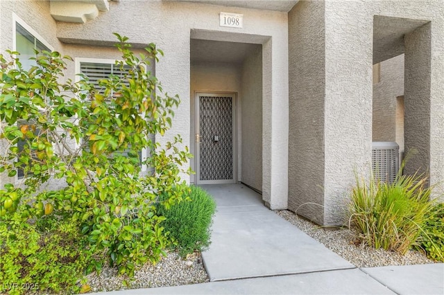 property entrance with stucco siding and cooling unit