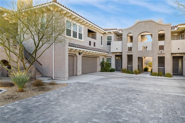 view of front of home with stucco siding, an attached garage, driveway, and a tile roof