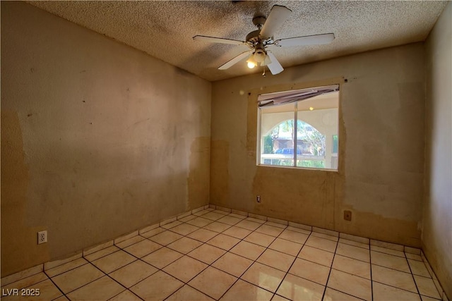 empty room featuring light tile patterned floors, a textured ceiling, and a ceiling fan