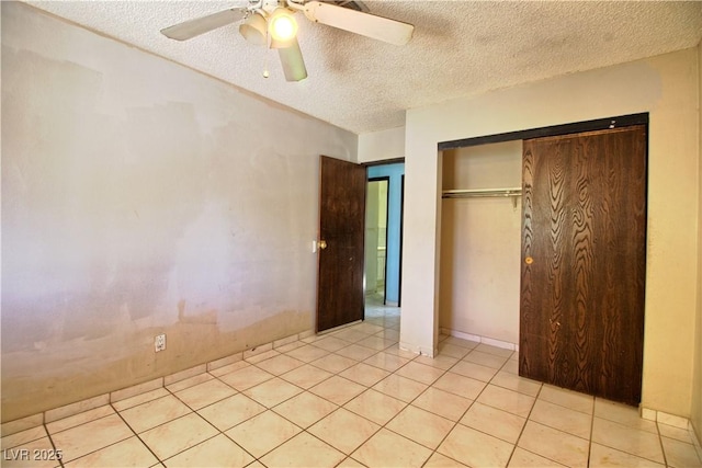 unfurnished bedroom featuring light tile patterned floors, a closet, a textured ceiling, and ceiling fan