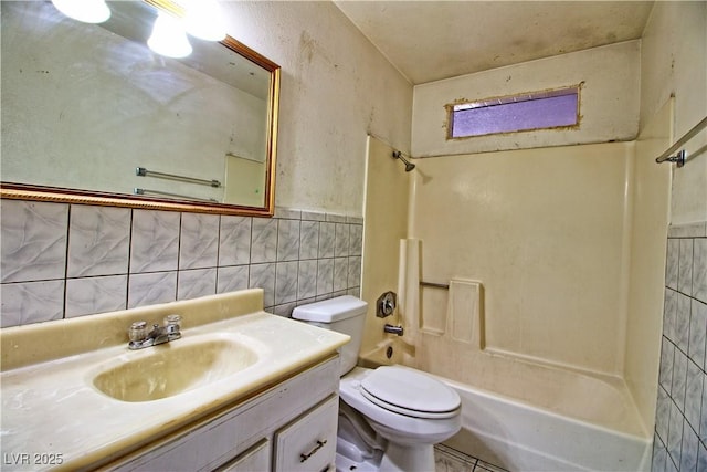 bathroom with tub / shower combination, toilet, tile walls, and vanity