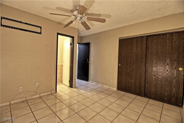 unfurnished bedroom featuring a closet, a textured ceiling, light tile patterned flooring, and a ceiling fan