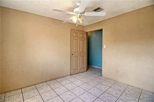 spare room featuring light tile patterned floors, visible vents, a textured ceiling, and ceiling fan