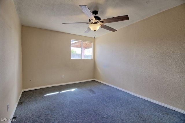 spare room featuring dark colored carpet, baseboards, a ceiling fan, and a textured wall