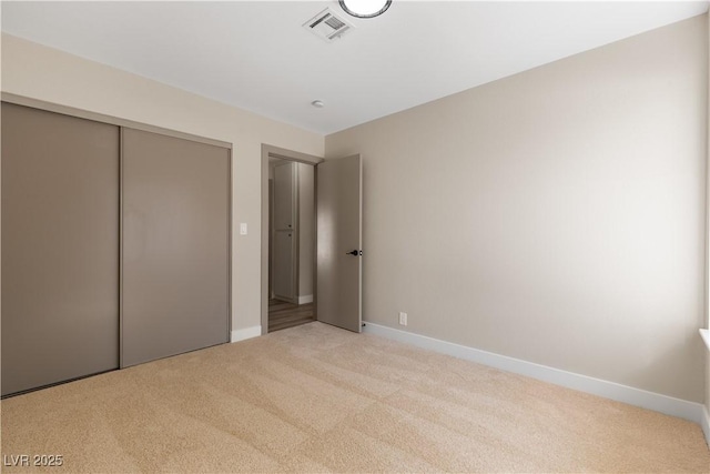 unfurnished bedroom featuring baseboards, visible vents, a closet, and light carpet