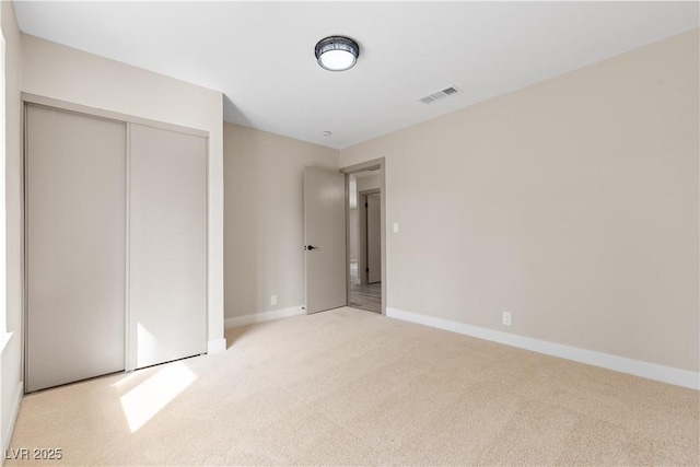 unfurnished bedroom featuring visible vents, baseboards, carpet, and a closet