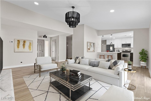 living room featuring an inviting chandelier, recessed lighting, light wood-style floors, and baseboards