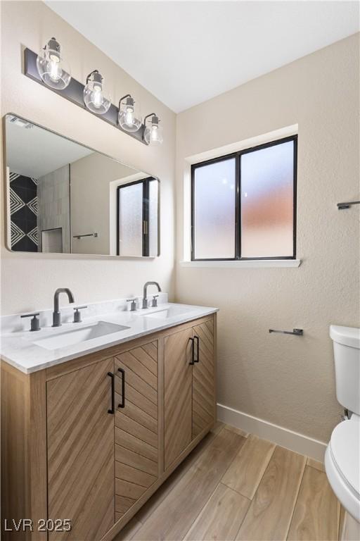 full bathroom featuring a sink, baseboards, toilet, and wood finished floors